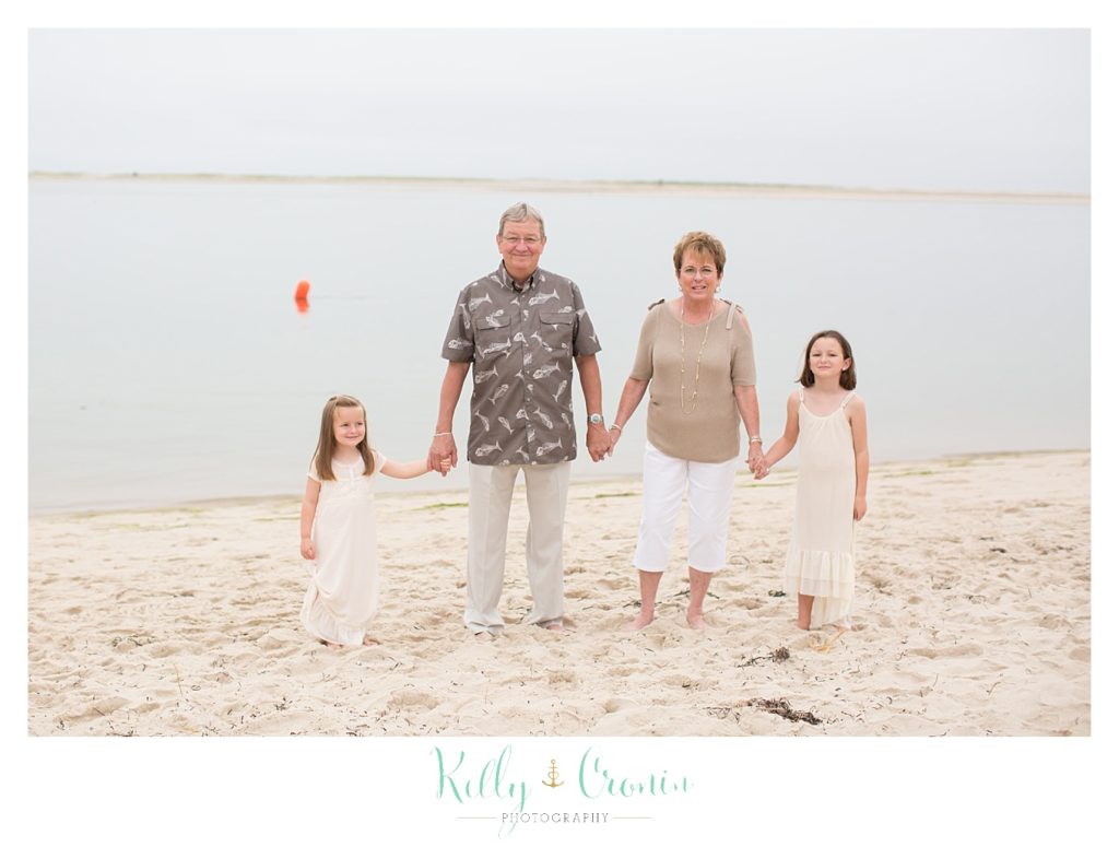 Grandparents stand with their two granddaughters holding hands