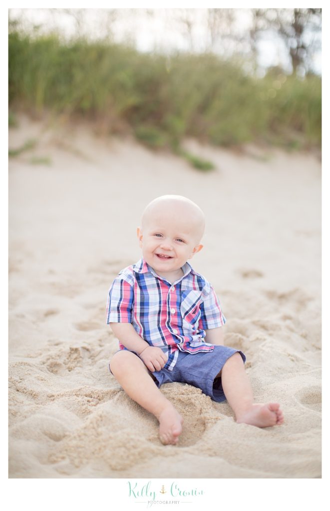 A baby boy plays in the sand. 