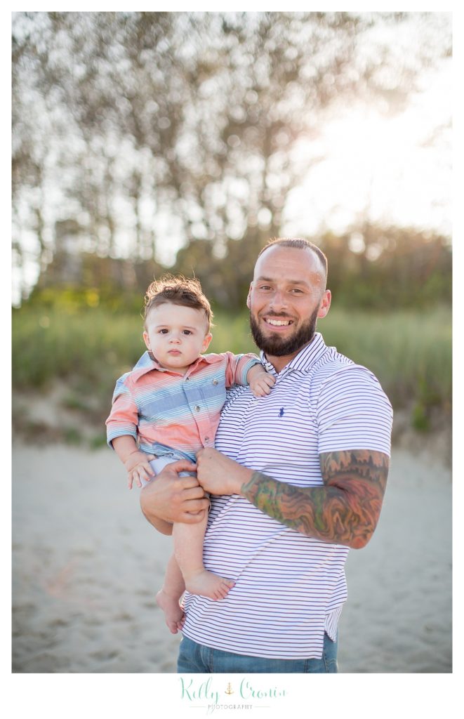 A man with a tattoo sleeve holds his baby. 