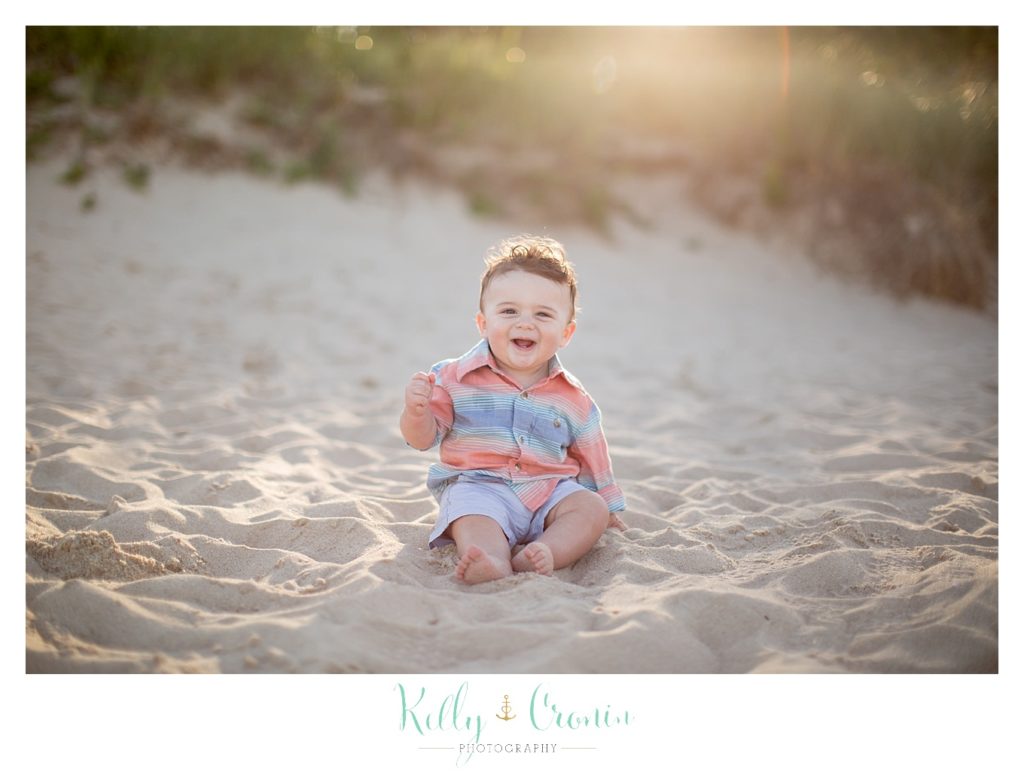 A baby boy sits on the beach for a special cake smash session. 