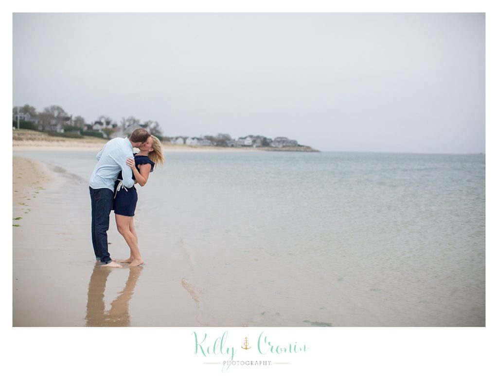 A man gives his fiance a kiss on the beach | Cape Cod Engagement Photographer 
