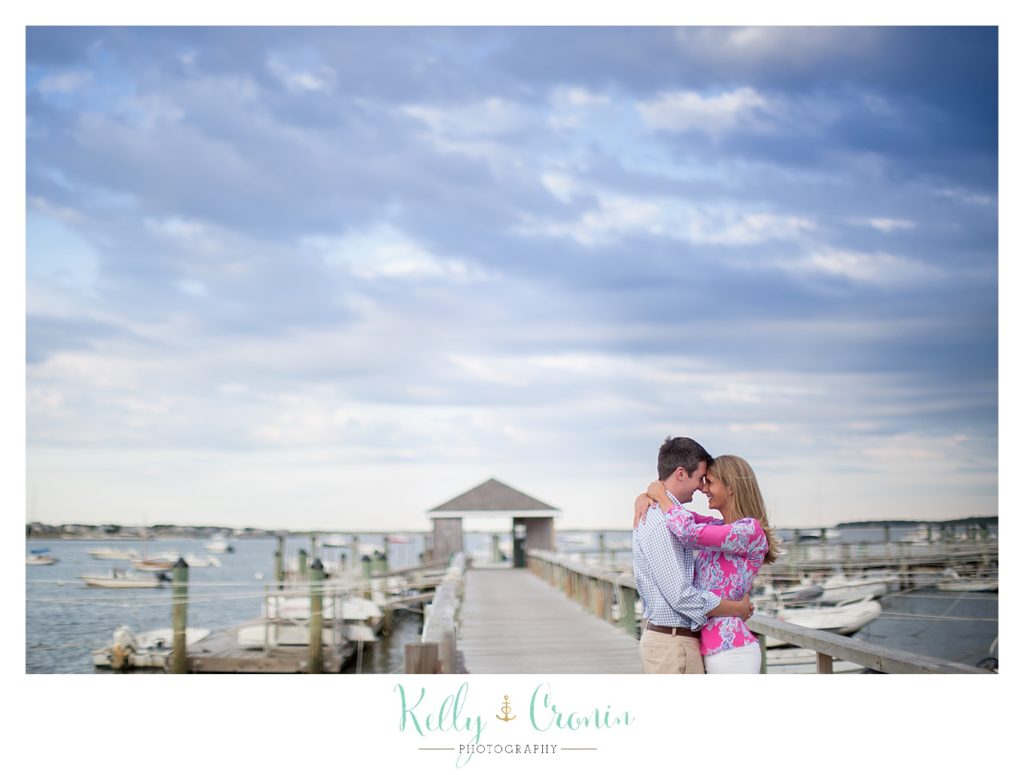 A man embraces his fiance on a dock during their engagement photos. 