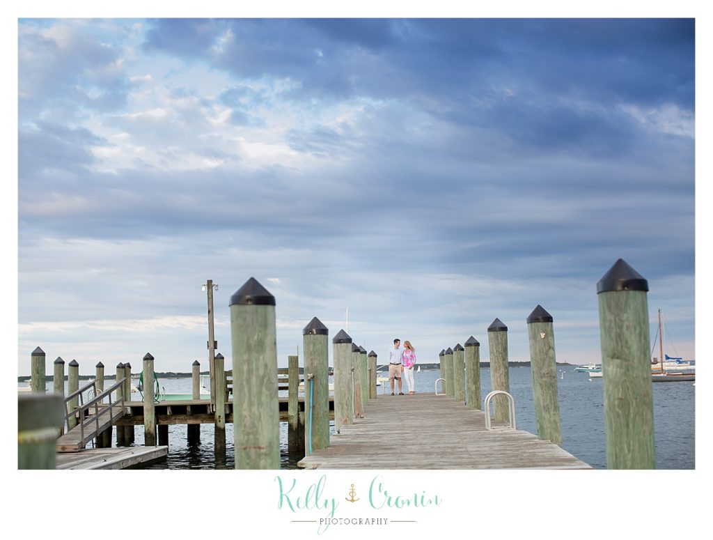 A couple walk down a pier during their engagement photos. 