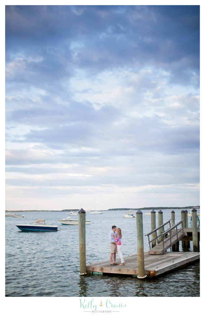 A couple kiss while standing on a dock in Cape Cod. 