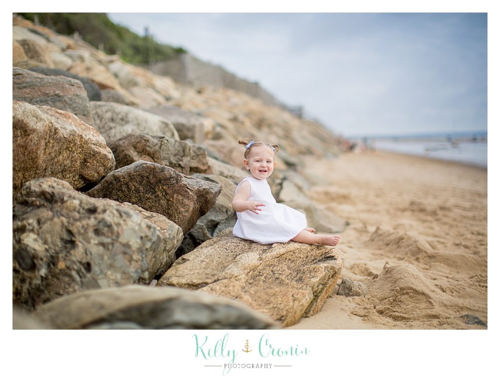A baby sits on some rocks for some beach photos. 