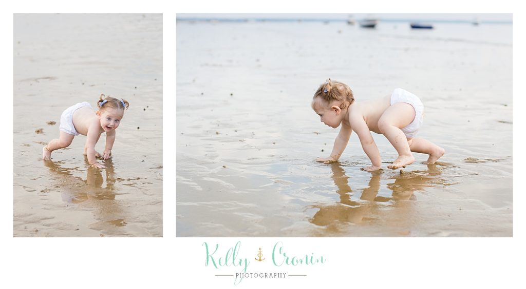 A baby wears her diaper and crawls in the water. 
