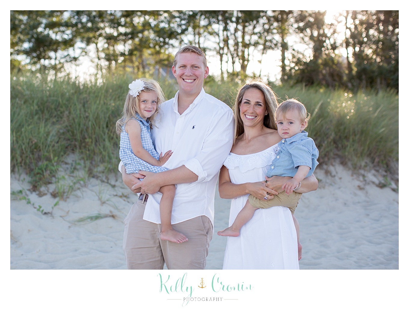 A family of four poses for a beach family photography session.