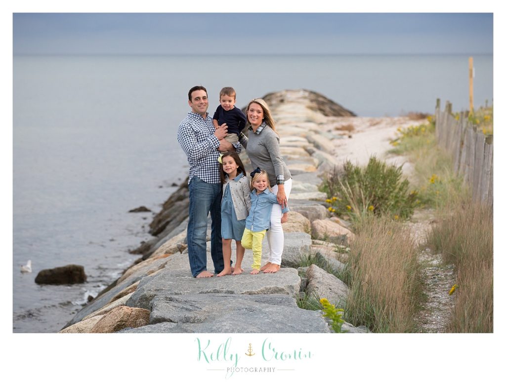 A family stands together on a pier for their family photos. 