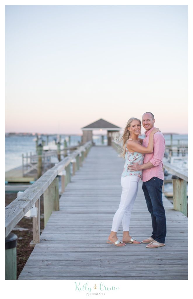 A couple stand on the pier for their Cape Cod Engagement Photos. 