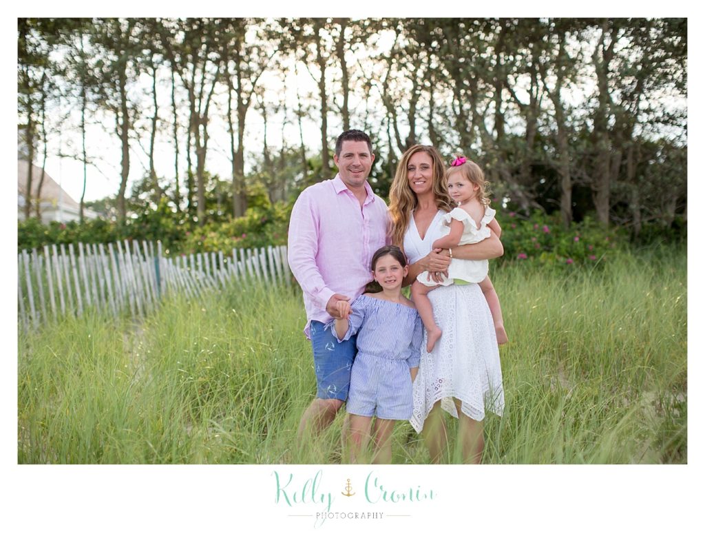 A family stands in some tall green grass for their Outdoor Family Photos. 