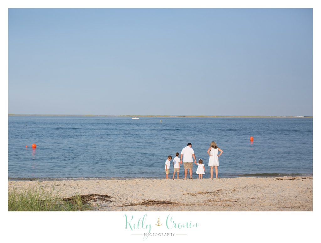 A family stands at the shoreline during their Cape Cod photography session. 