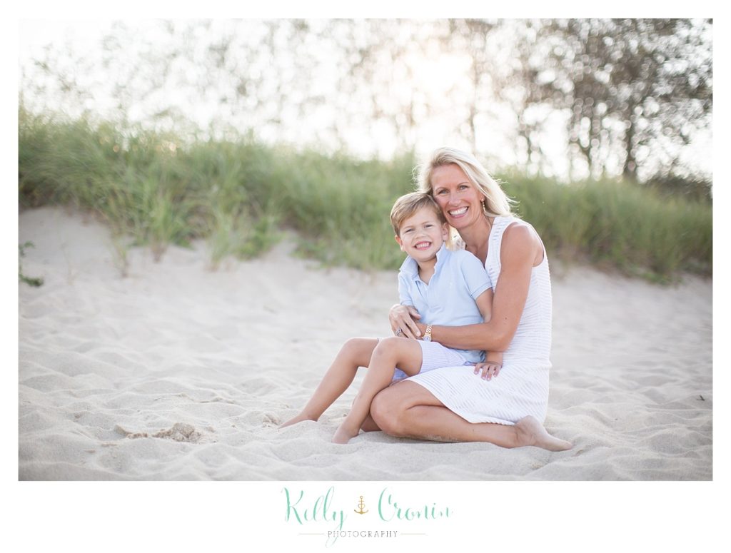 A mother holds her son on her lap during their beach photos. 