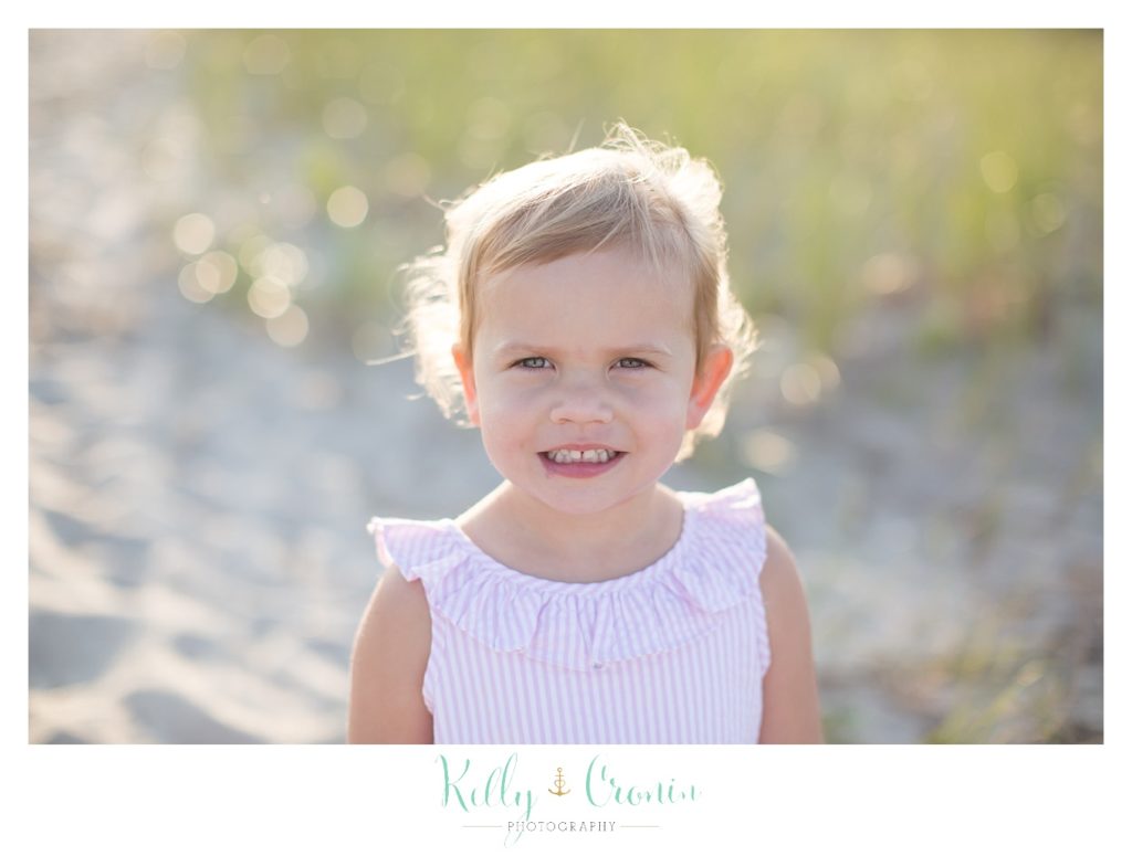 A small girl smiles for some family beach photos. 