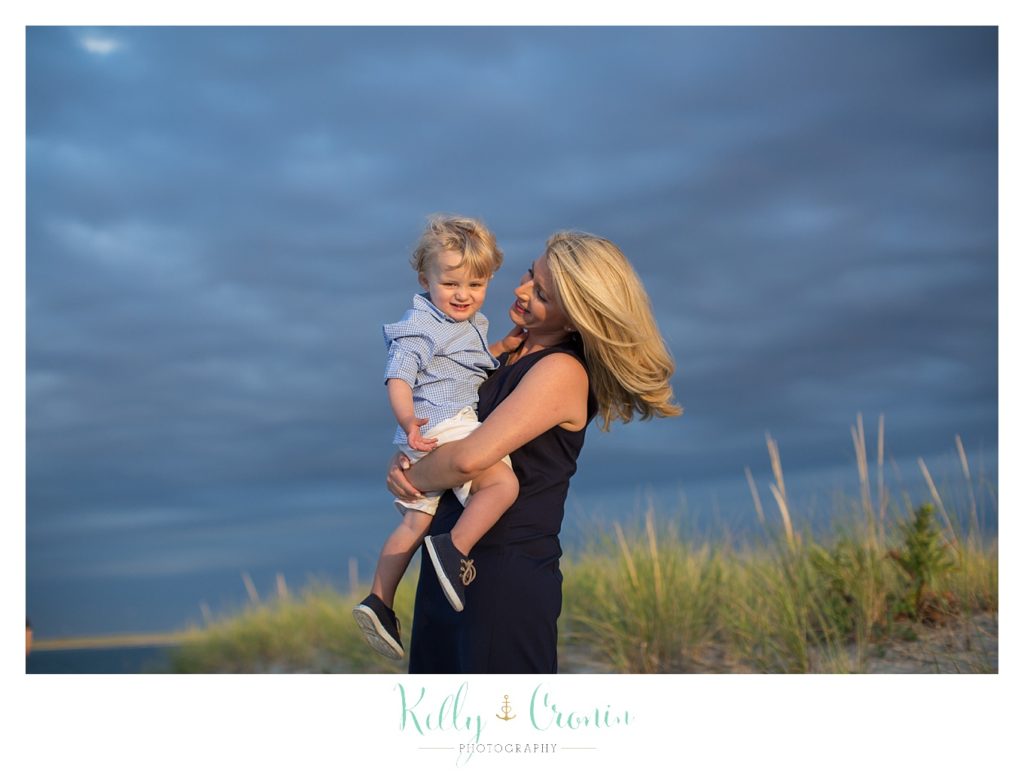 A mother holds her son and swings him around. 