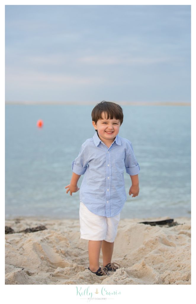A boy is walking on the beach in Cape Cod. 