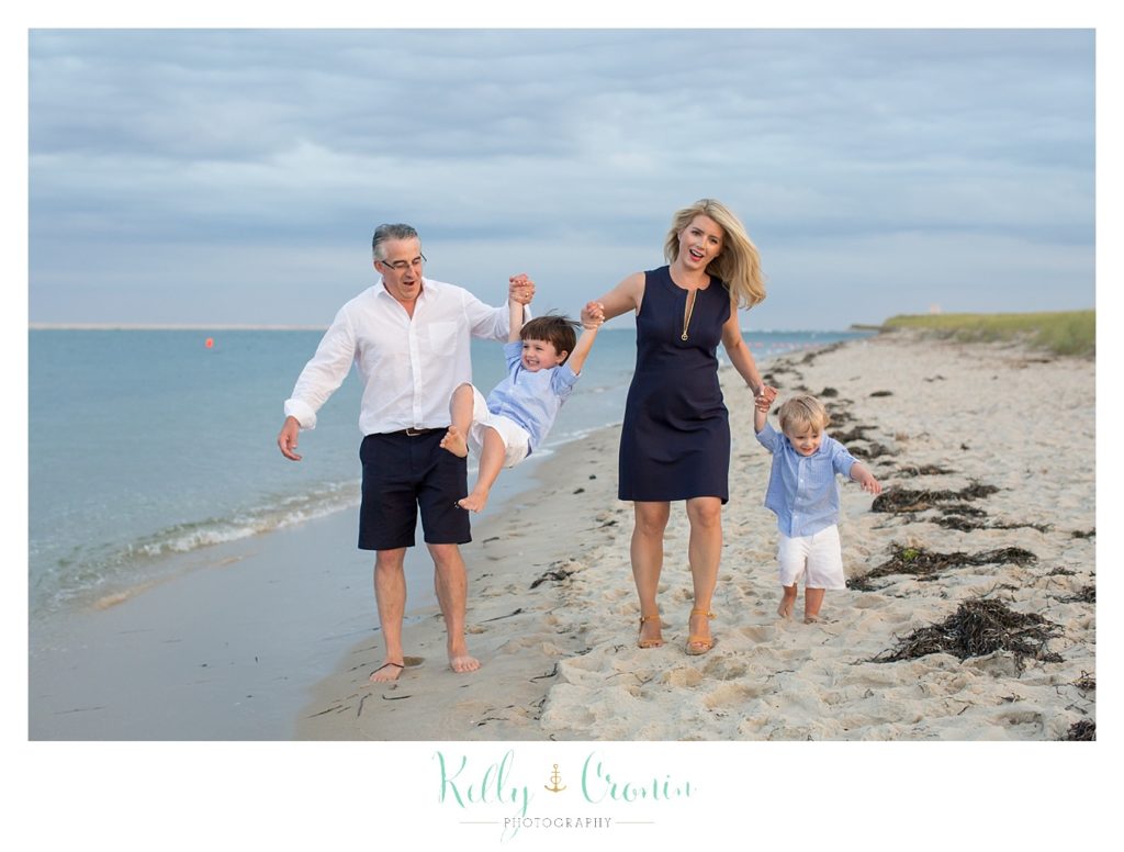 Parents swing their son between them. 