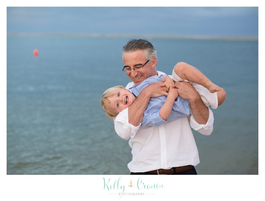 A man lifts his son up to tickle him. 