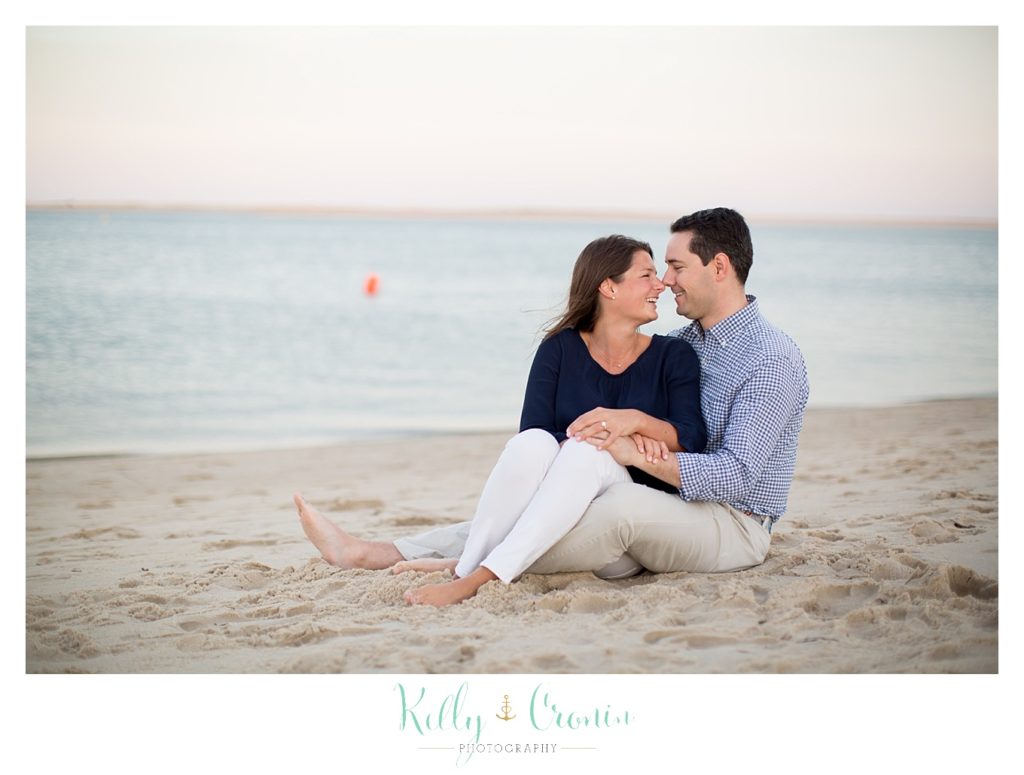 A couple cozies up together on the beach to celebrate their Cape Cod engagement. 