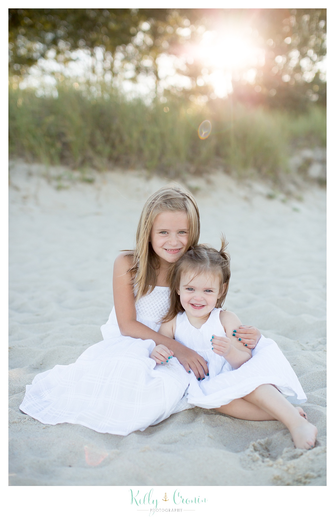 A girl hugs her little sister during Family Pictures In Cape Cod.