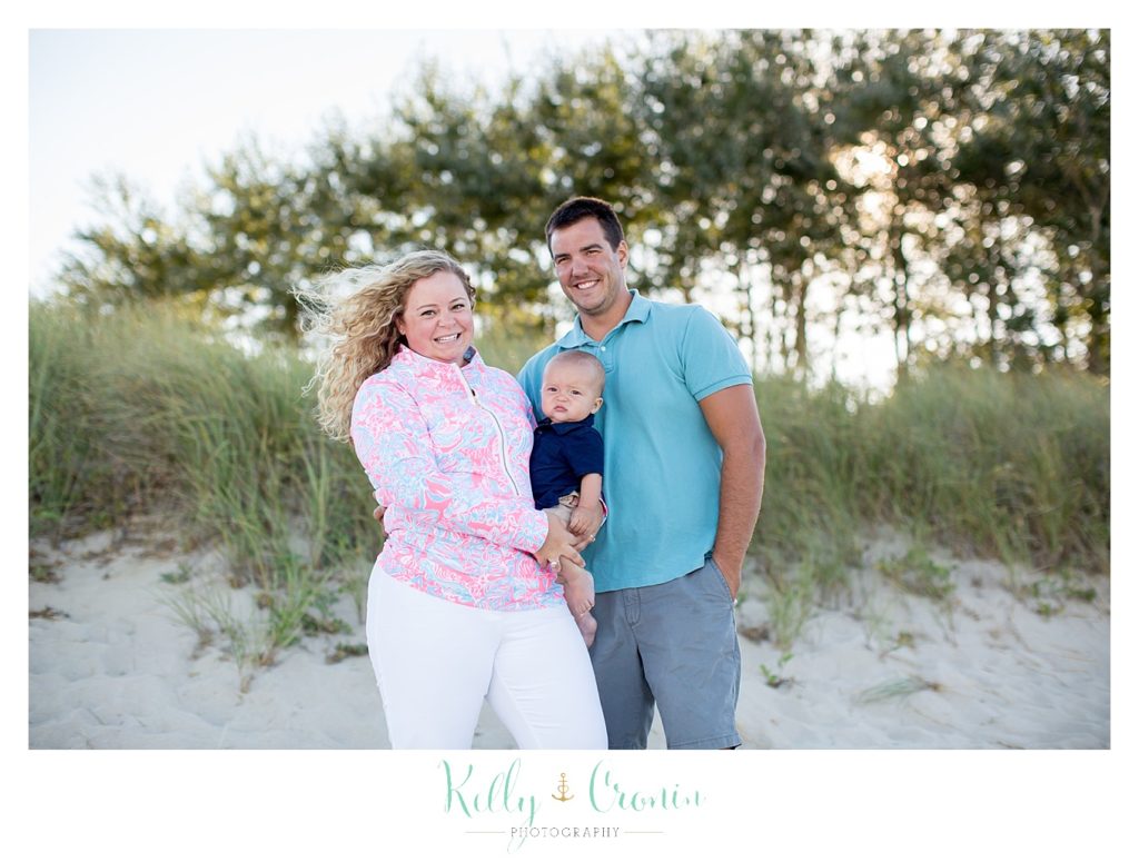 Two parents hold their baby as they pose for Family Pictures In Cape Cod. 