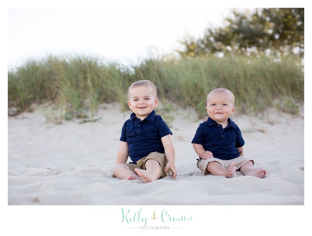 Two baby brothers sit in the sand for Family Pictures In Cape Cod. 