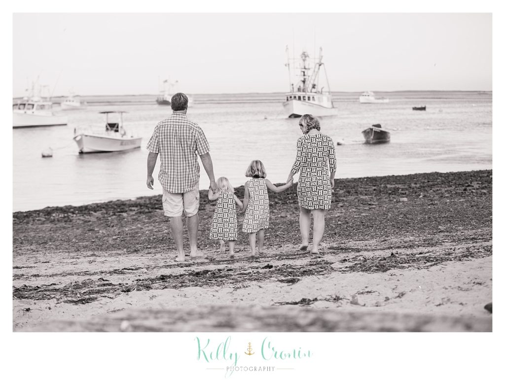 A family holds hands and walks on the beach. 