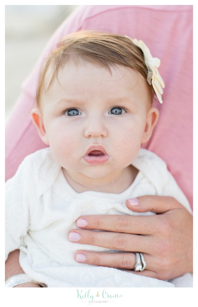 A baby girl with blue eyes gives a serious look. 