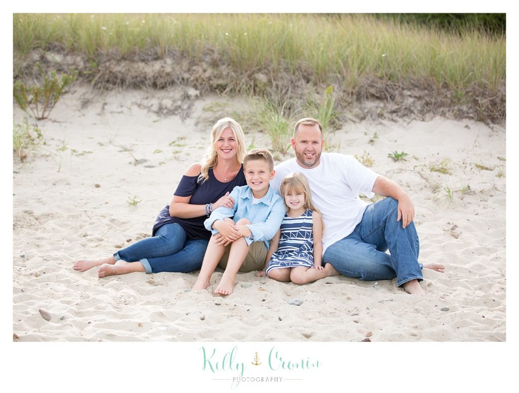 A family sits in the sand | Mini Family Photo Sessions