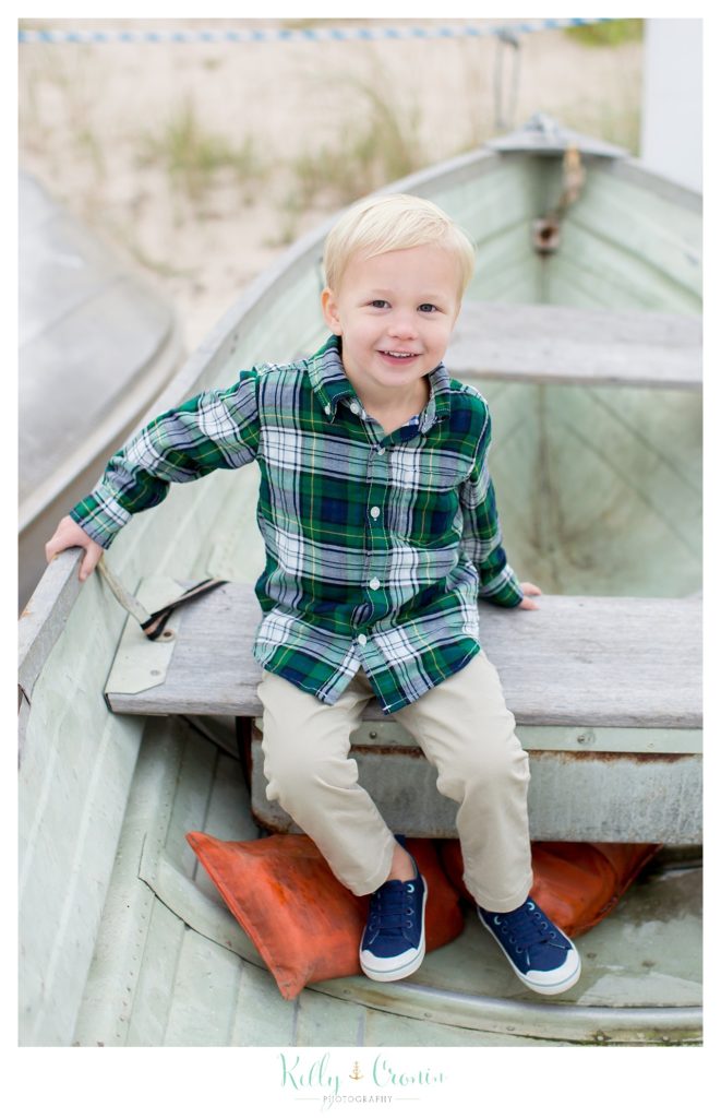 A boy in a plaid shirt sits in a boat. 
