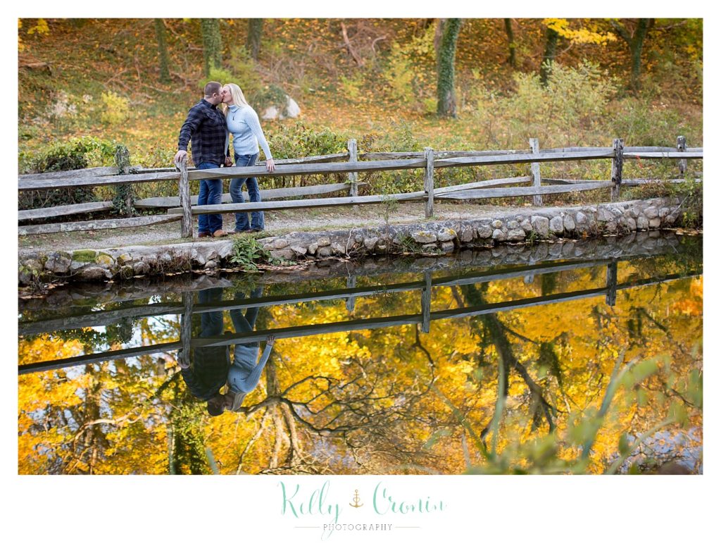 A couple stand among yellow leaves during their Engagement Pictures In Cape Cod. 