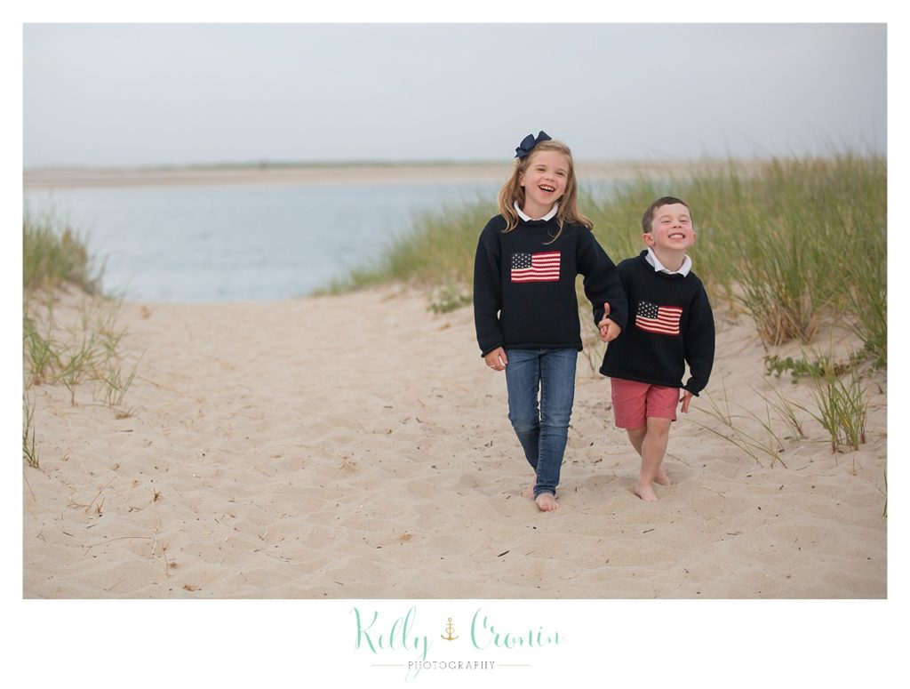 Children walk along the shore, holding hands. 
