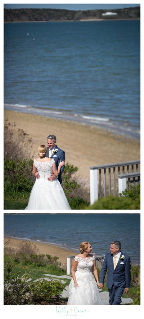 A bride and groom hold each other in front of the beach. 
