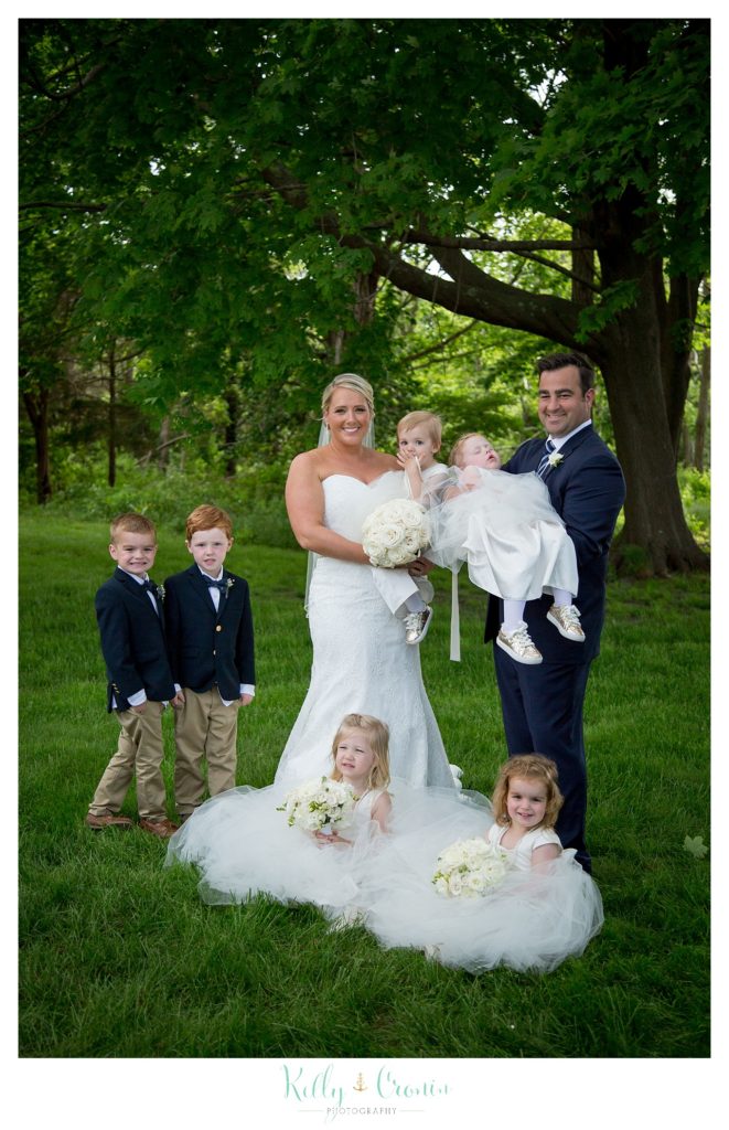A bride and groom pose with their flower girls and ring bearers. 