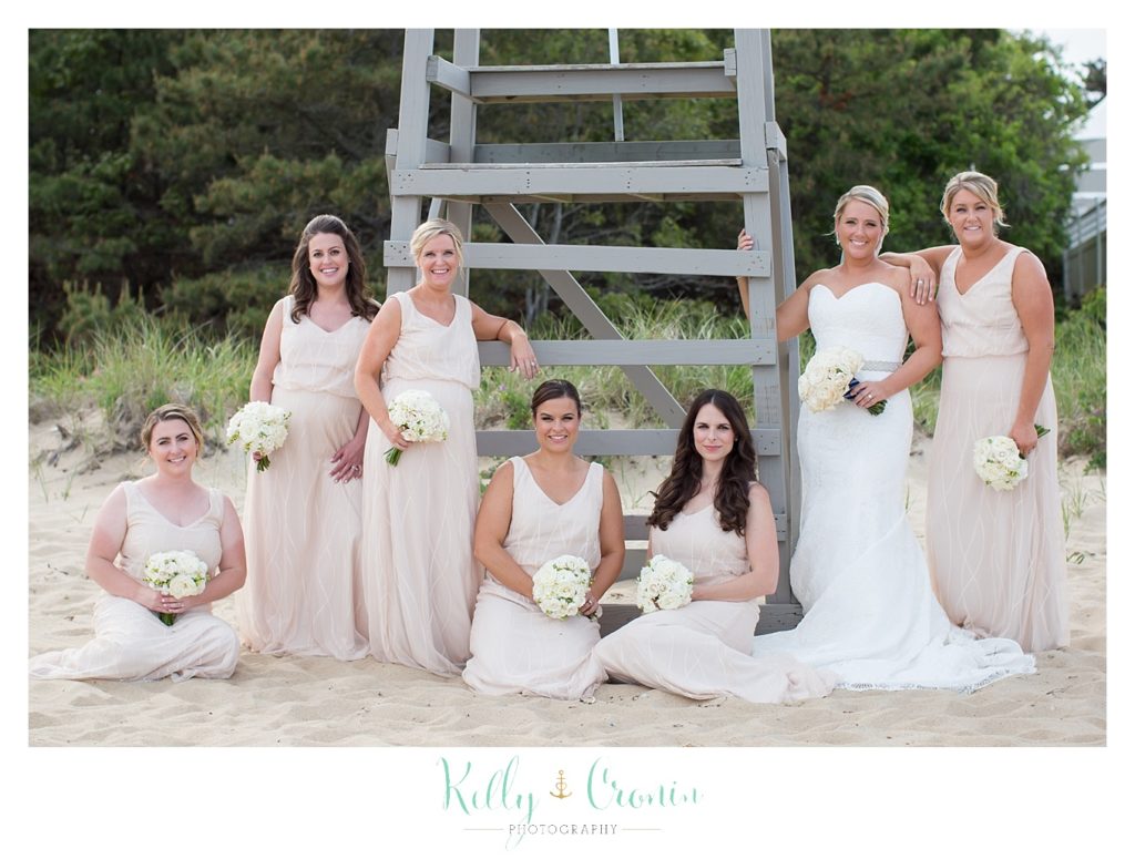 A bride poses with her bridal party on the beach. 