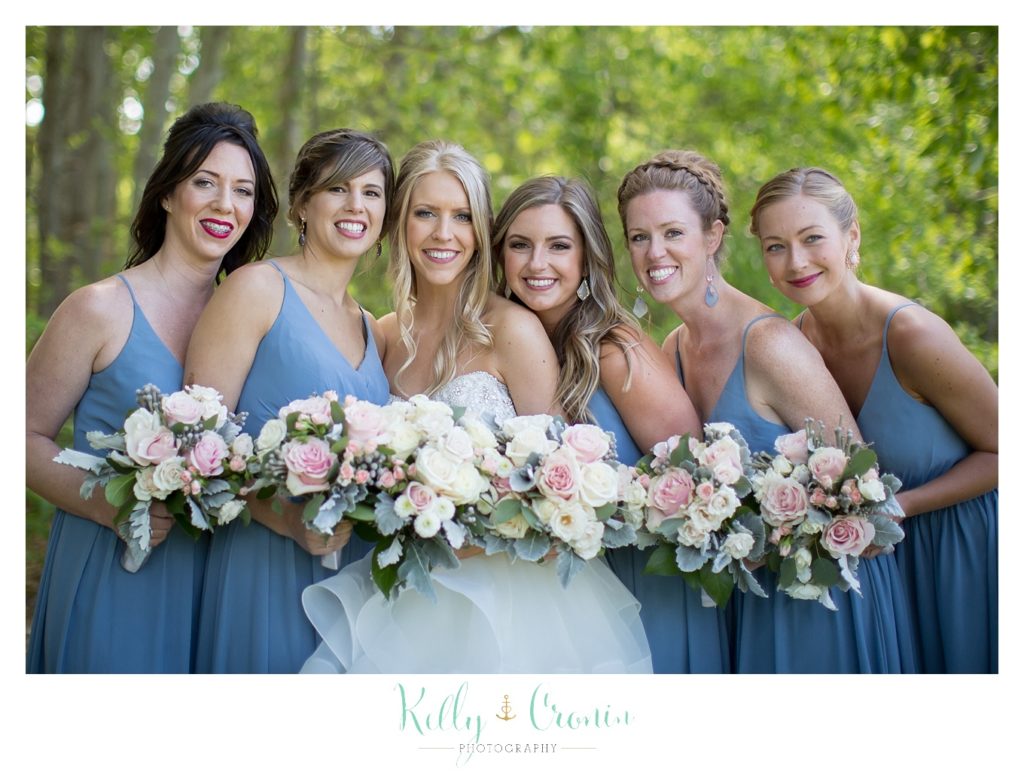 A bridal party holds up their bouquets. 