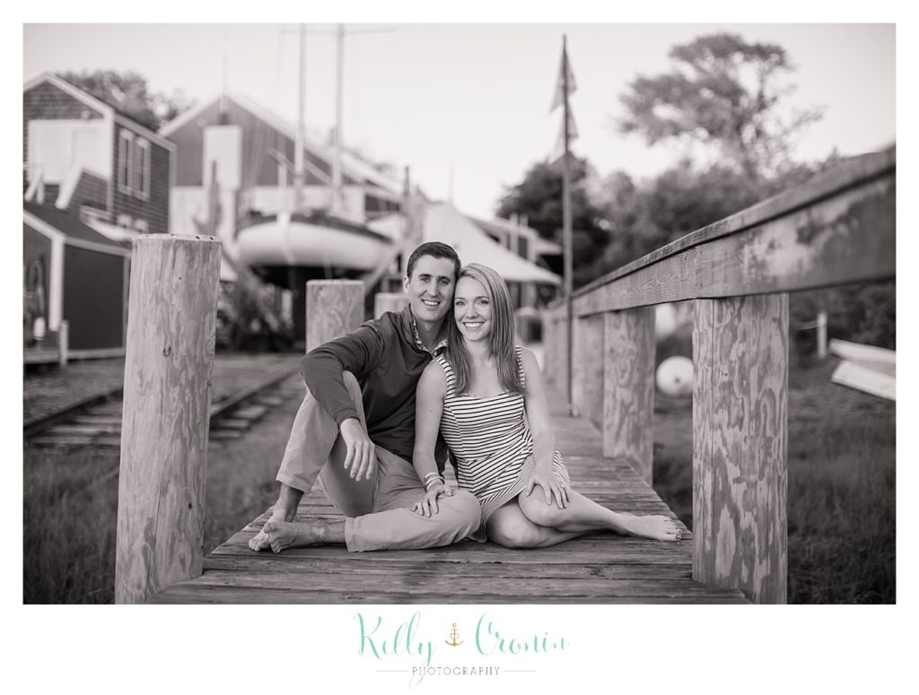 An Engagement Photographer captures a couple sitting on a bridge. 