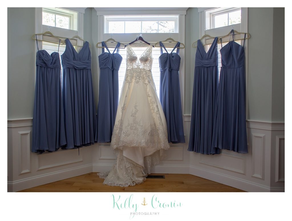 Bridal party dresses hang in a window. 