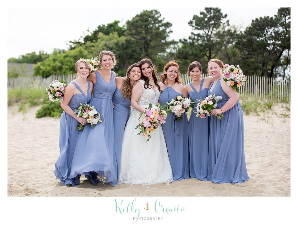 A bride poses with her bridal party on the beach. 