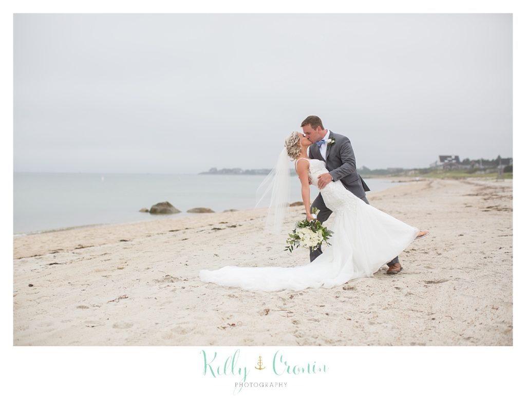 A man dips his bride in a kiss after their Bourne Farm Wedding. 