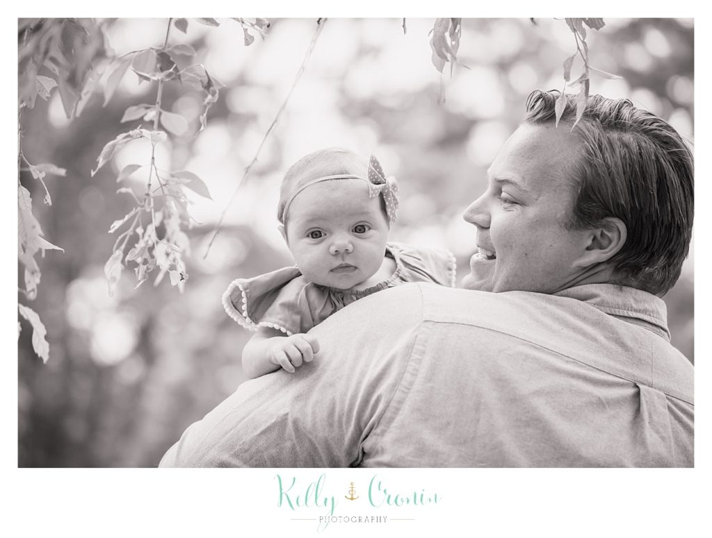 A man holds his baby over his shoulder during some Wildflower Mini Sessions. 