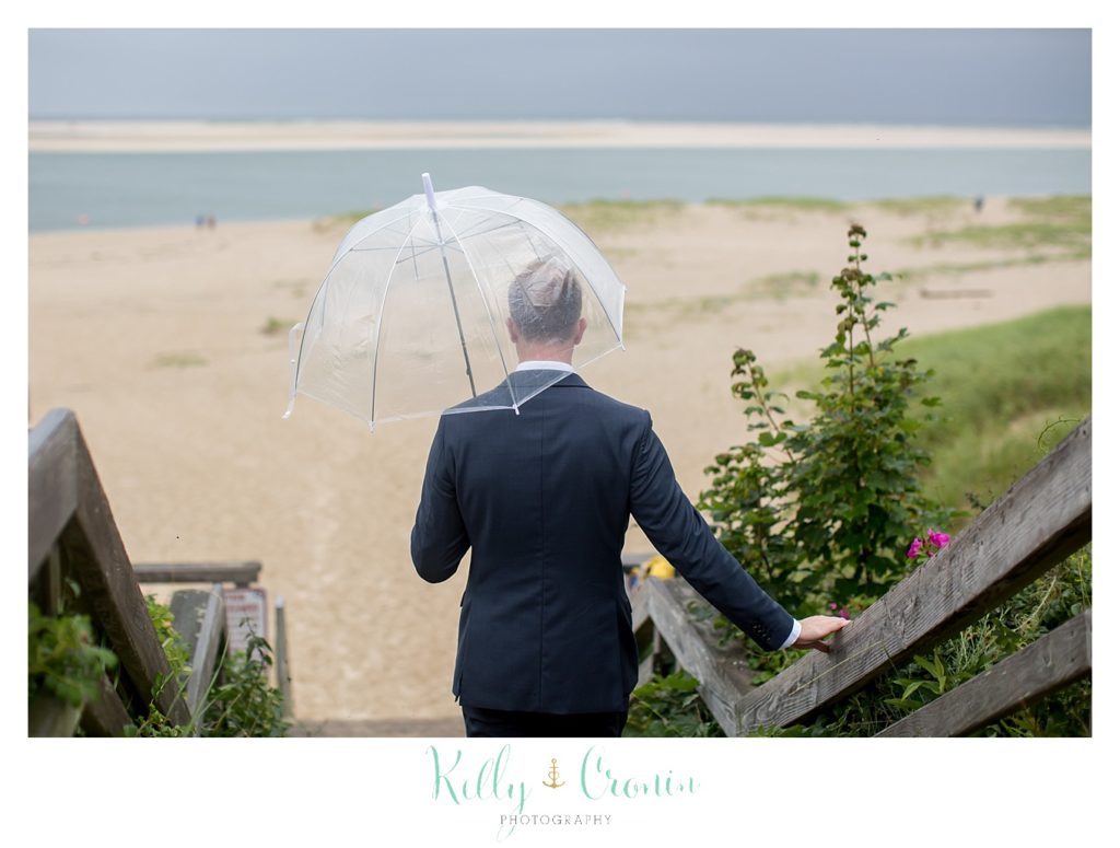A groom holds an umbrella. 