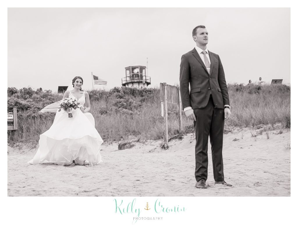 A bride runs out to meet her groom on the beach. 