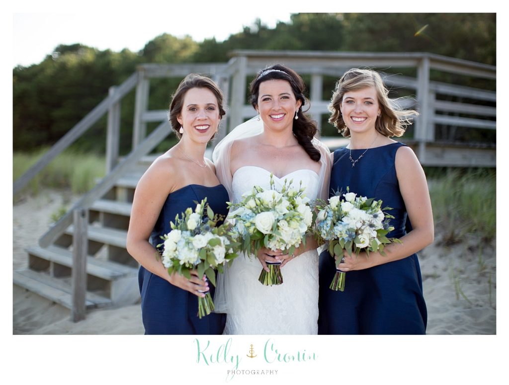 A bride stands next to two of her bridesmaids.