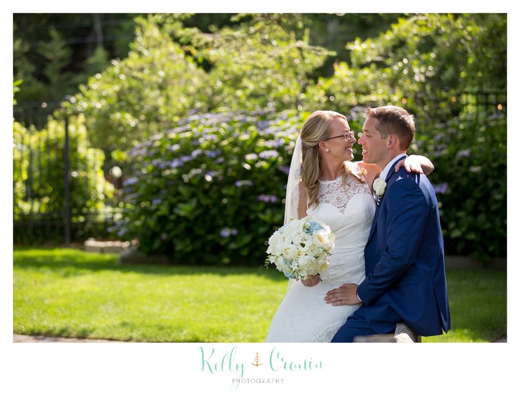 A woman wraps her arm around her groom's neck for a kiss. 