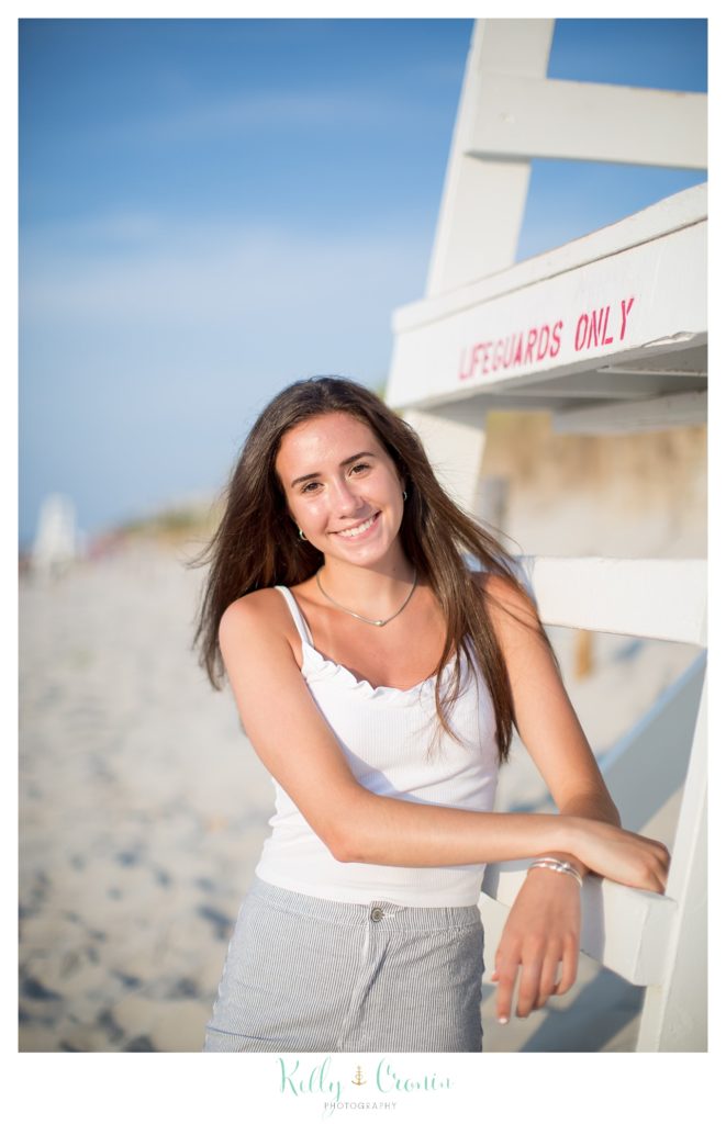 A teenager stands on the beach for her senior portraits. 
