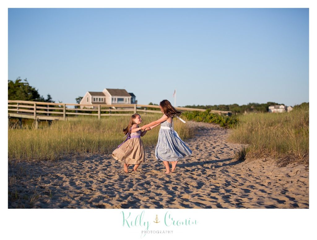 Two young sisters dance in the sand at Ridgevale beach. 