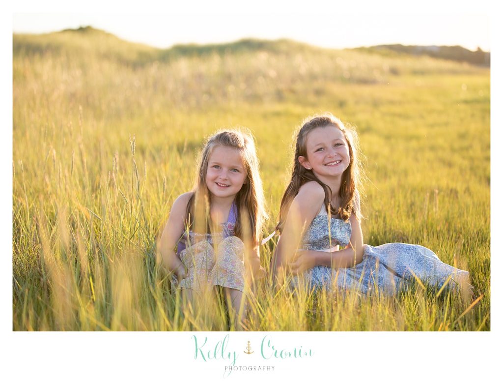Two sisters sit in a field of tall grass near Ridgevale Beach. 