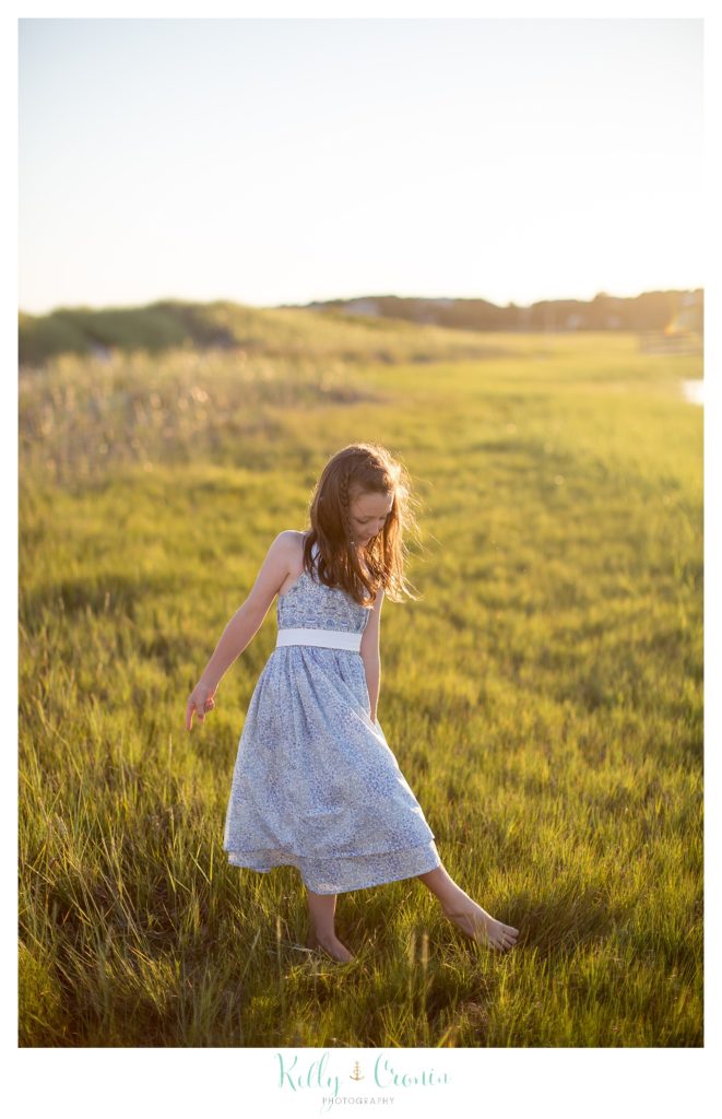 A little girl walks through some tall grass. 