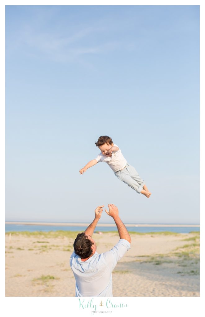 A daddy throws his toddler up into the air to play. 