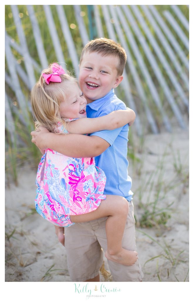 A young boy holds his younger sister for a big hug. 